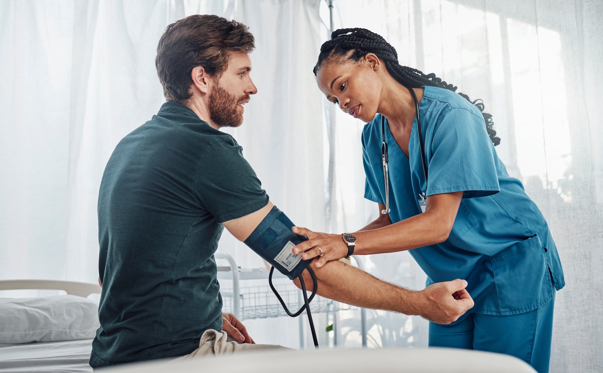 Nurse, doctor and man with blood pressure test in hospital for heart health or wellness. Healthcare